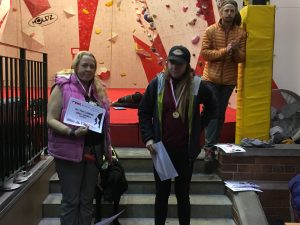 Photograph of me stood on the left hand side of stone steps with a silver medal and certificate with Fizz stood beside me and fellow climber and gold medal winner Abi on the right