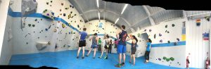 Panoramic photograph of the room hosting the competition in VauxWall with people stood around and some climbing 