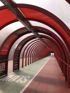 Second photograph shows the arch of the red girders forming over the top of the passageway looking down on the ramp with the green and red path for cycles and pedestrians.