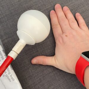 Ambutech High milage roller tip on the end of red and white cane, with my hand to the right for size comparison 